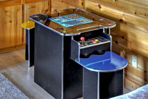 A small, enclosed arcade machine with a joystick and buttons, placed in a wooden cabin.