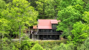 Ein zweigeschossiges Gebäude mit rotem Dach, umgeben von dichtem, grünen Wald.