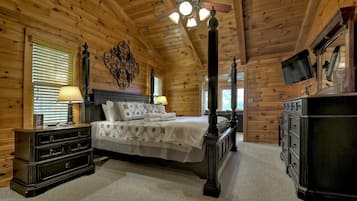 Une chambre dans une cabane en rondins, avec un lit à baldaquin, une commode en bois et un ventilateur de plafond.