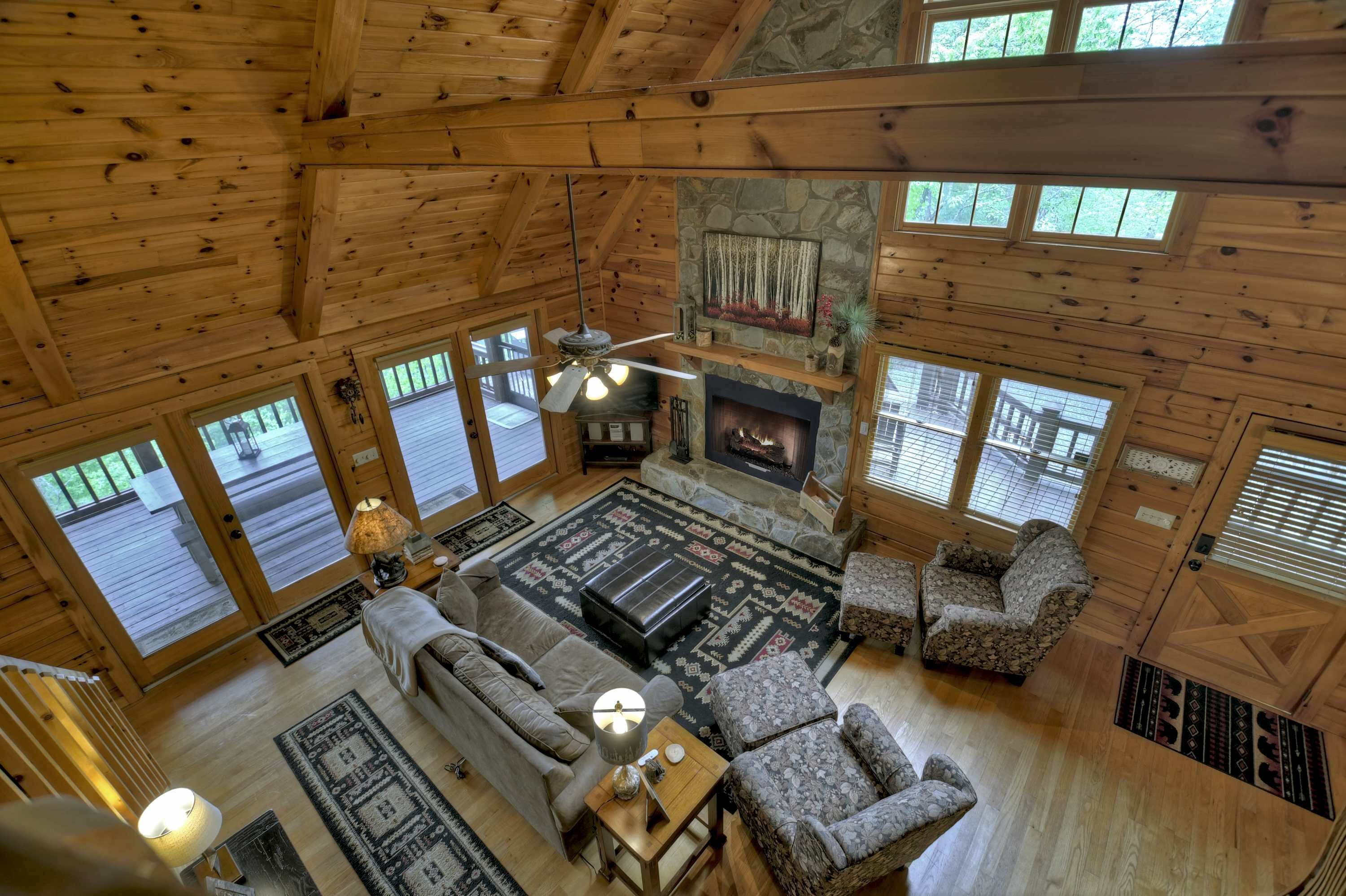 A spacious living room with a fireplace, wooden floors, and large windows.