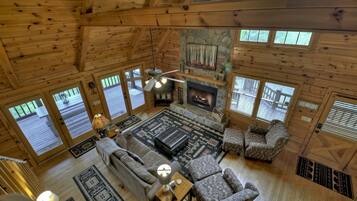A spacious living room with a fireplace, wooden floors, and large windows.