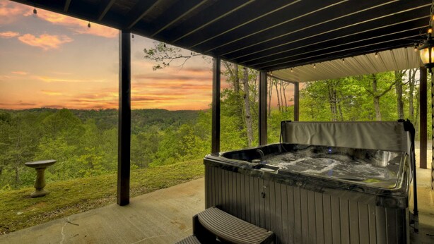 Ein Whirlpool mit Sitzbank, ein Vogelbad und Blick auf eine bewaldete Landschaft.