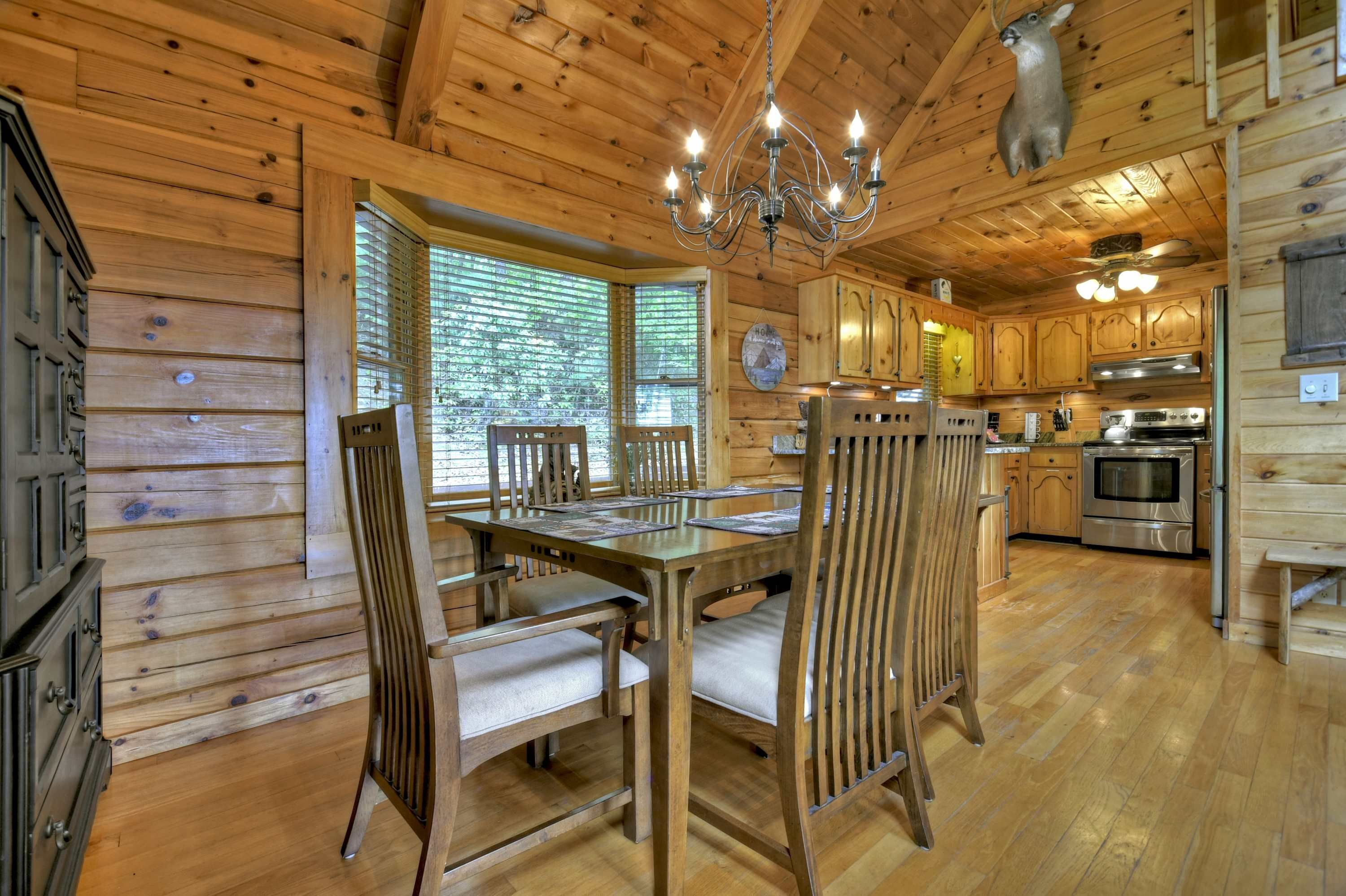 L’intérieur d’un chalet en bois comprend un coin repas, une cuisine et un lustre.