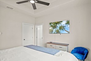 A bedroom with a bed, a ceiling fan, a TV on the wall, a desk, and a chair. - Latitude Adjustment Boat Slip Walk to Beach Pool (Corpus Christi)
