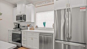 Una cocina moderna con armarios blancos, electrodomésticos de acero inoxidable y una ventana con vistas.