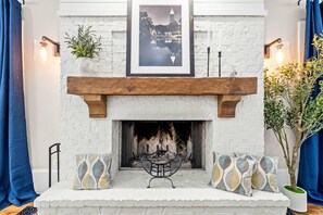 A fireplace with a white brick surround, a wooden mantel, and a framed picture above. - 10 Mins to Mercedes-benz Stadium Dog Friendly (Atlanta)