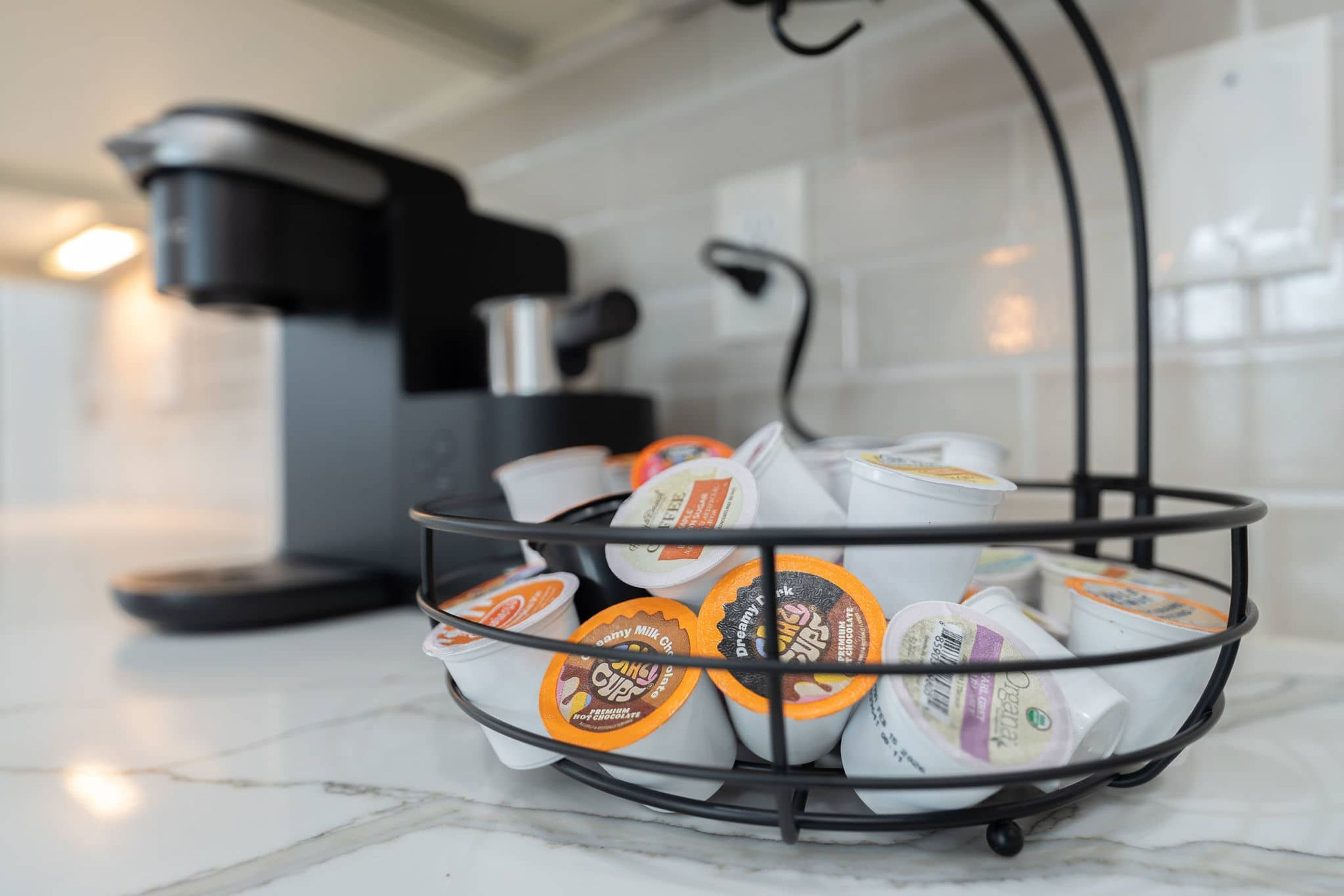 A kitchen counter with a coffee machine and a basket containing various packaged food items.