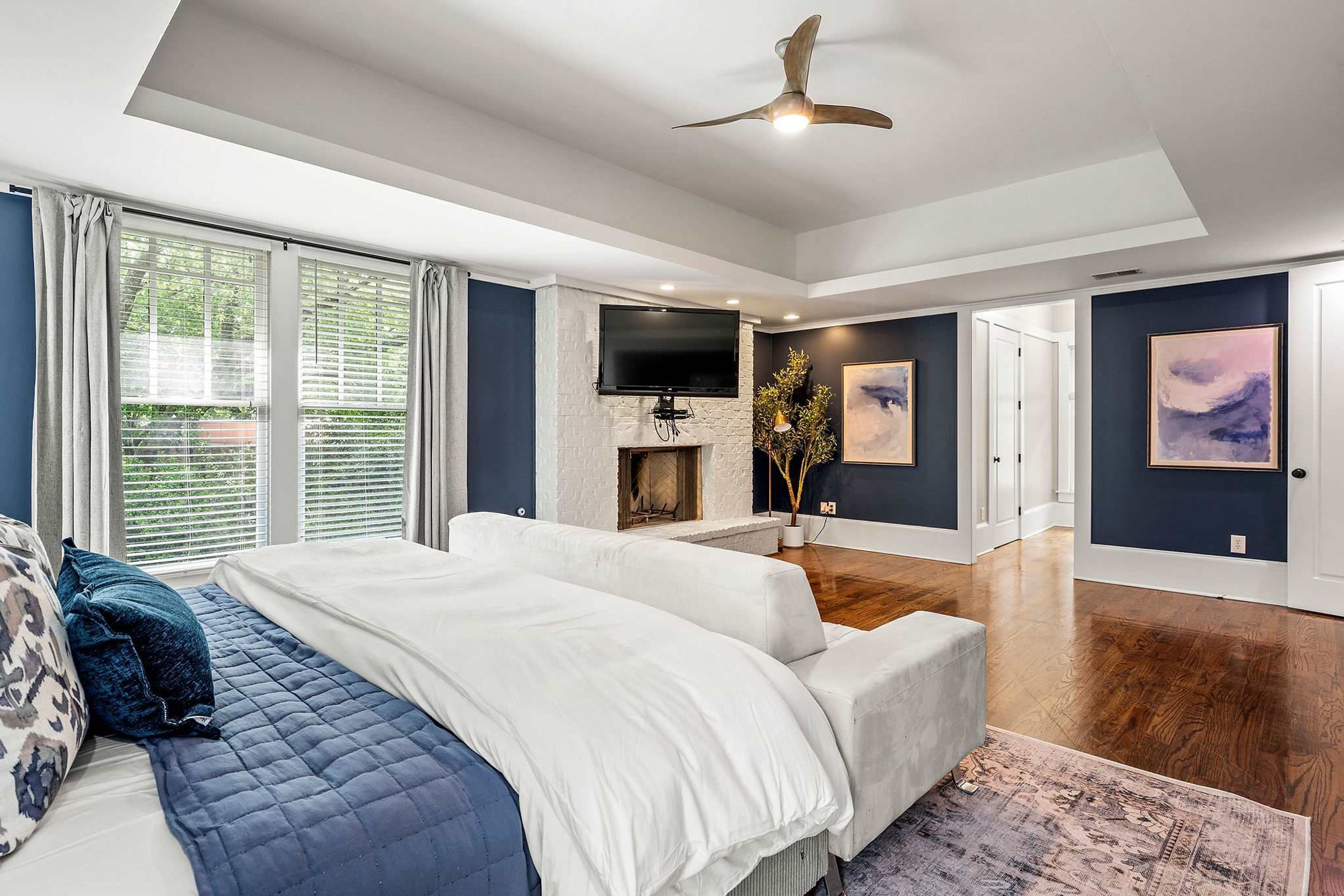 A modern bedroom with a large bed, a fireplace, a TV, and artwork on the walls.