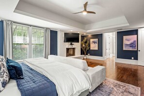 Ein modernes Schlafzimmer mit einem großen Bett, einem Kamin, einem Fernseher und Kunstwerken an den Wänden.