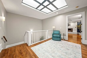 A spacious room with a skylight, wooden flooring, a white railing, and a patterned sofa. - 10 Mins to Mercedes-benz Stadium Dog Friendly (Atlanta)
