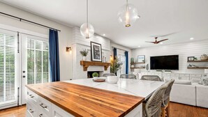 Cozinha moderna com ilha central, armários brancos e bancada de madeira.