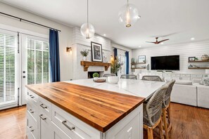 A modern kitchen with a central island, white cabinetry, and a wooden countertop. - 10 Mins to Mercedes-benz Stadium Dog Friendly (Atlanta)
