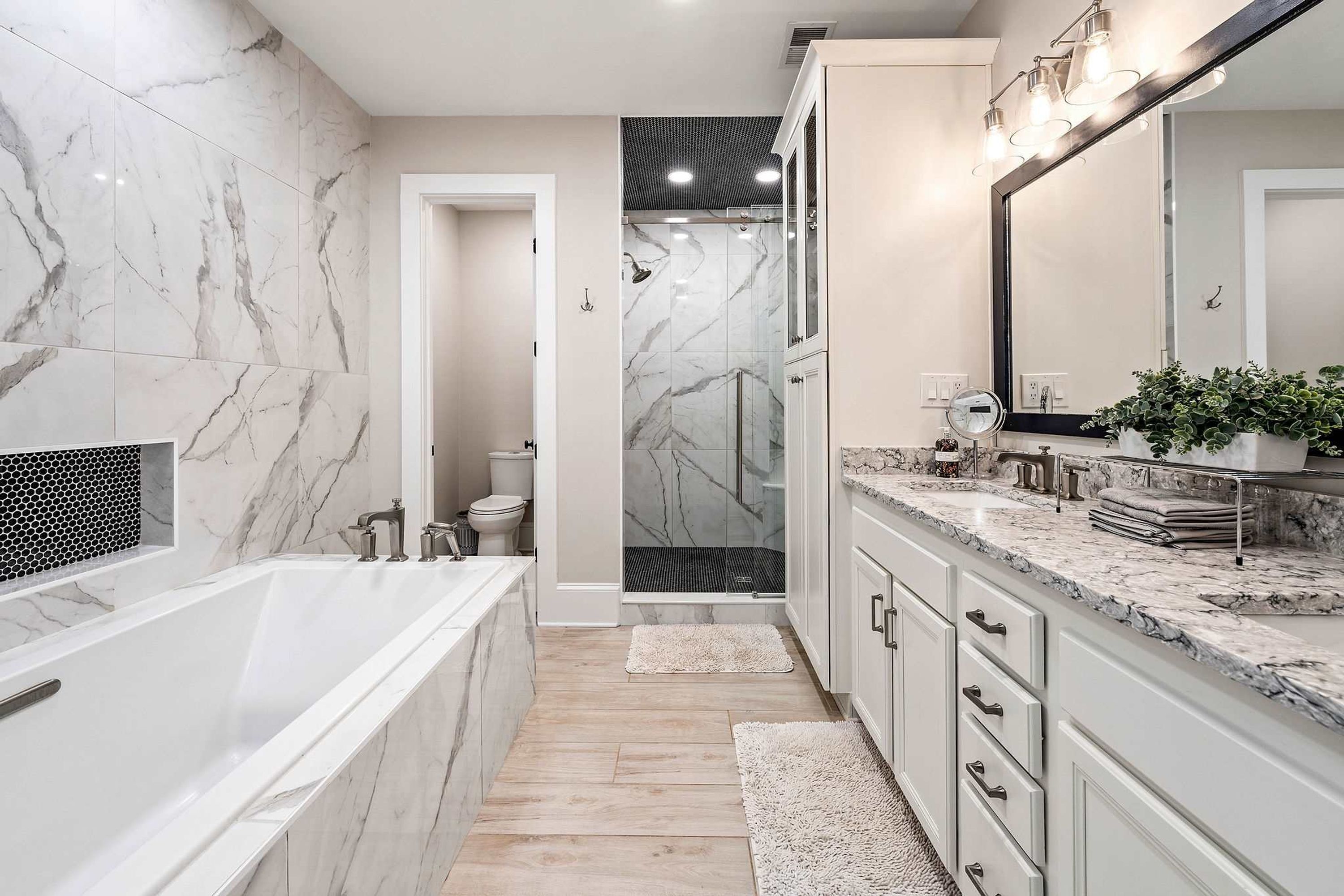 A modern bathroom with a large bathtub, a walk-in shower, and a vanity with a mirror.