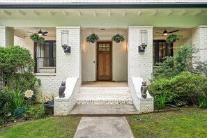 A house with a white brick exterior, a wooden front door, and a covered porch with two wall-mounted fans. - 10 Mins to Mercedes-benz Stadium Dog Friendly (Atlanta)