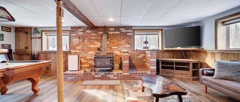 Ein gemütliches Wohnzimmer mit Kamin aus Backstein, Holzmöbeln und einem Fernseher.