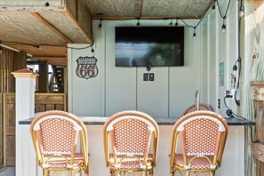 Uma área de bar com três cadeiras de vime, uma tela de televisão e um letreiro que diz 'Route 66'.