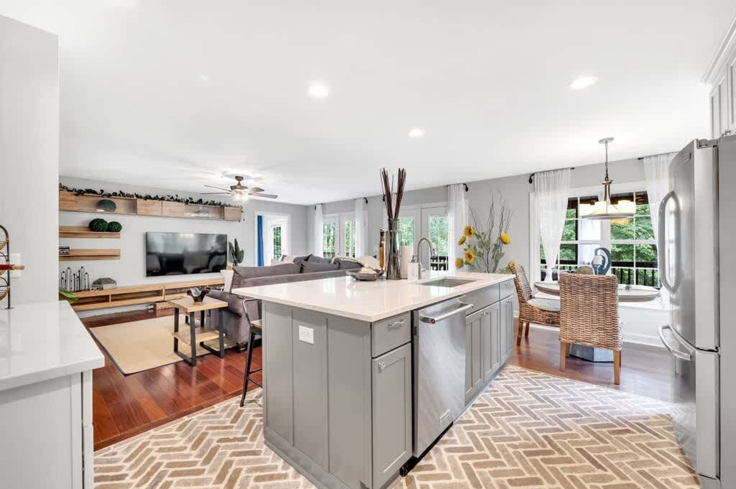 Una cocina moderna con una isla central, muebles grises y un lavavajillas integrado.