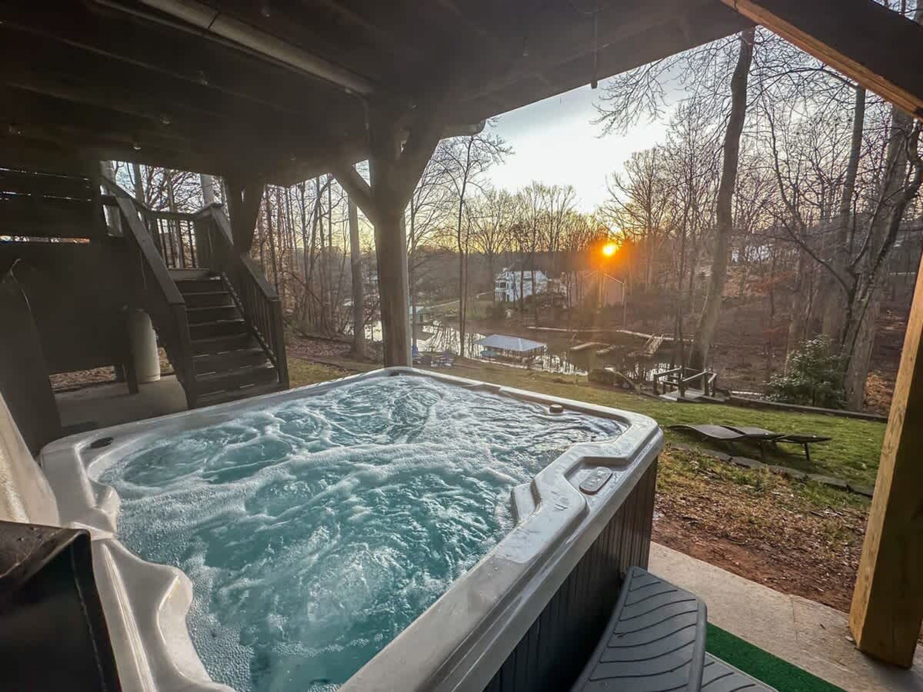 Un jacuzzi con vistas a un patio trasero y una casa al fondo.