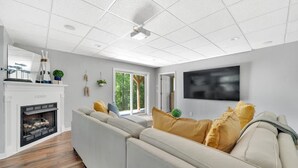 A modern living room with a sectional sofa, a fireplace, and a large flat-screen TV mounted on the wall. - Lakefront Villa Hot Tub Game Room Boat Lift (Mooresville)