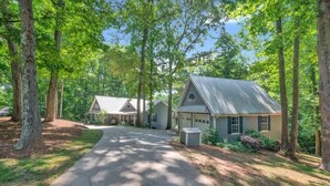 A residential property with a paved driveway leading to a house with a gabled roof and a garage. - Lakefront Villa Hot Tub Game Room Boat Lift (Mooresville)
