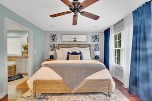 A bedroom with a bed, bedside tables, a ceiling fan, and artwork on the walls. - Lakefront Villa Hot Tub Game Room Boat Lift (Mooresville)