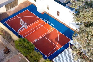 Ein Basketballplatz im Freien neben einem Gebäude mit weißer Fassade.