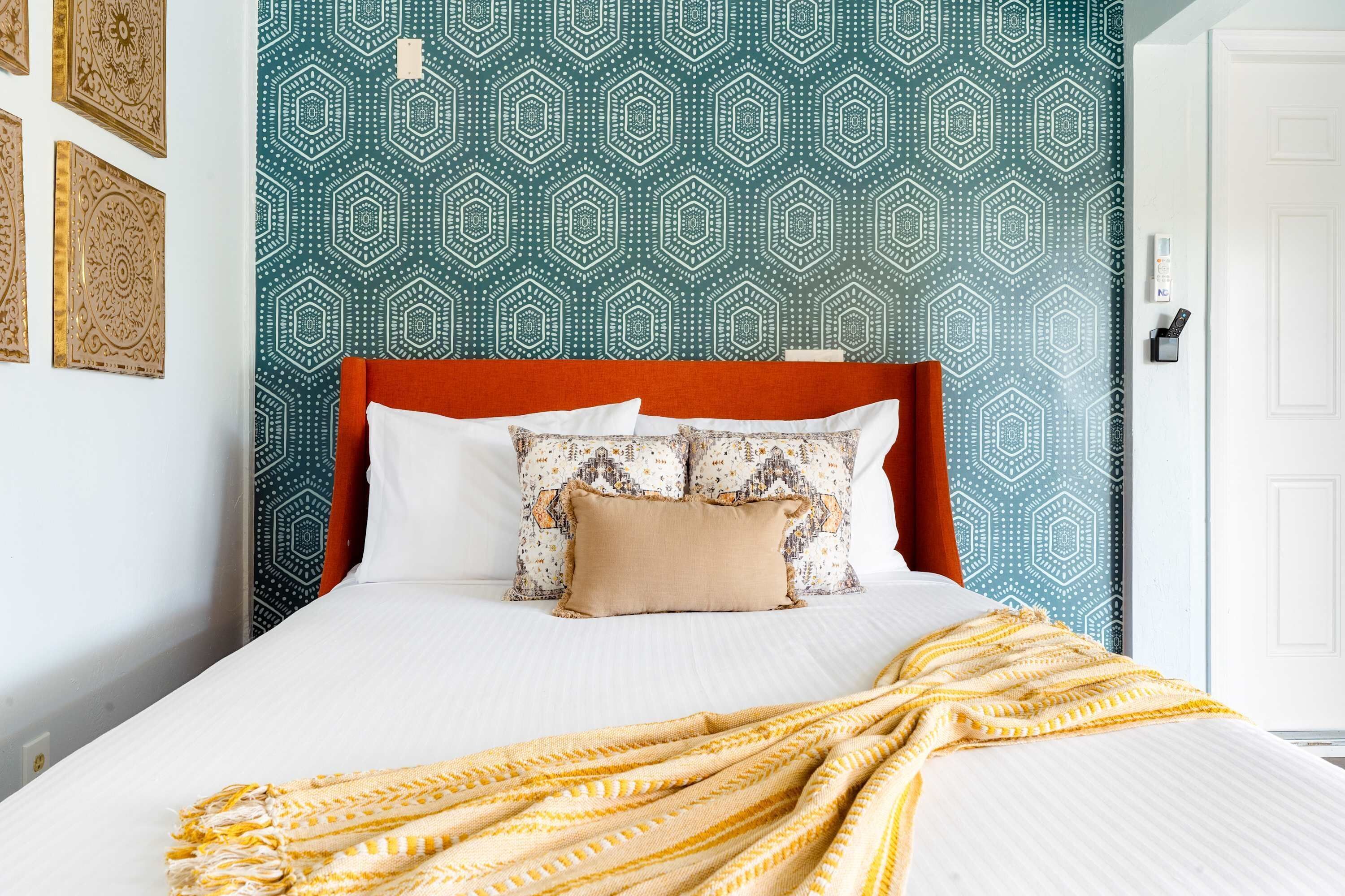 Un lit avec une couette blanche, plusieurs oreillers et un plaid jaune.