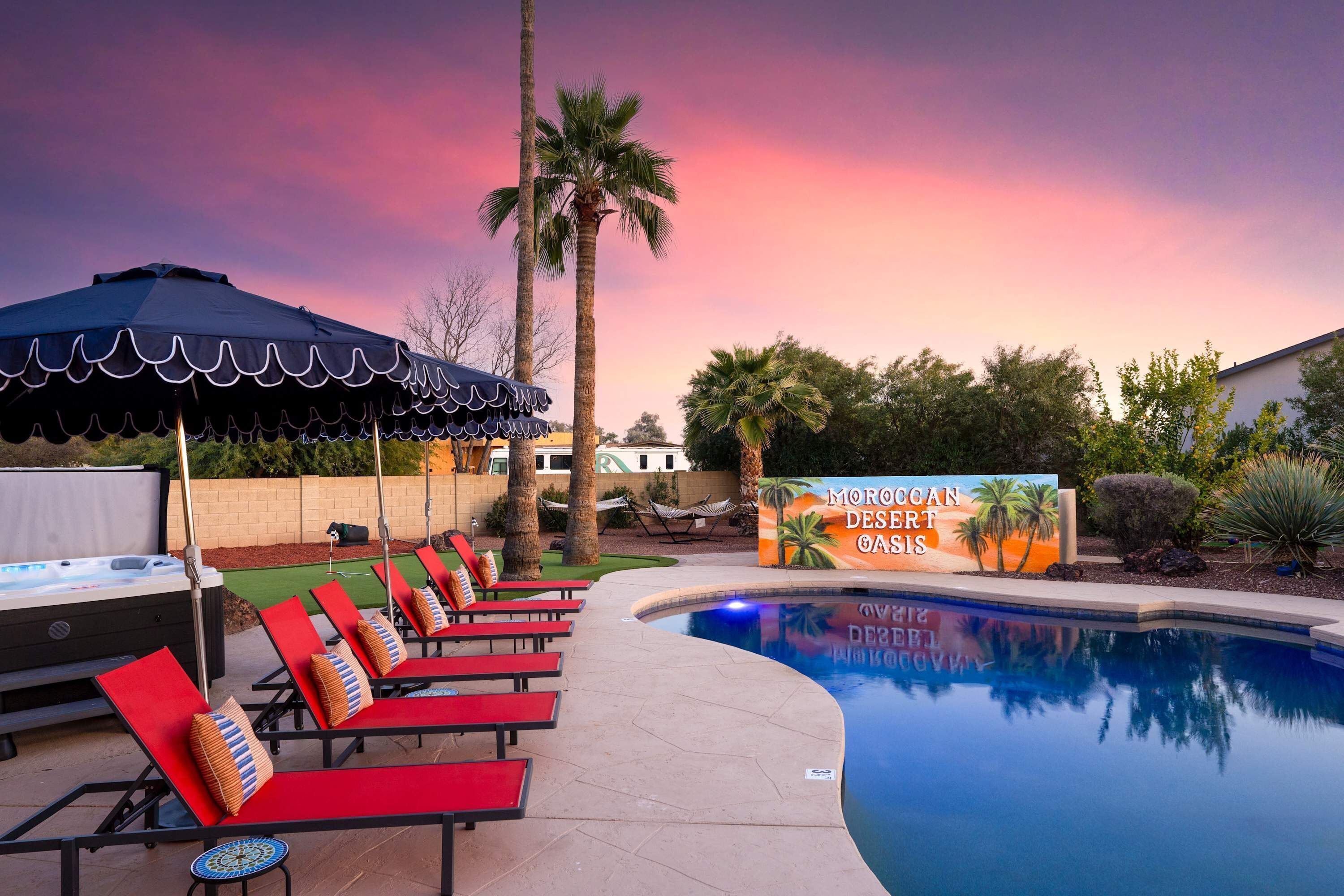 A pool area with lounge chairs and a hot tub.