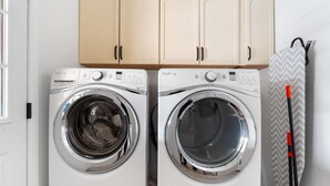 Two front-loading washing machines in a laundry room with wooden cabinets above. - Sleeps 24 Free Heated Pool Pickleball Theater (Scottsdale)