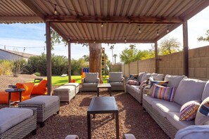 An outdoor patio with wicker furniture, a covered area, and a view of the backyard. - Sleeps 24 Free Heated Pool Pickleball Theater (Scottsdale)
