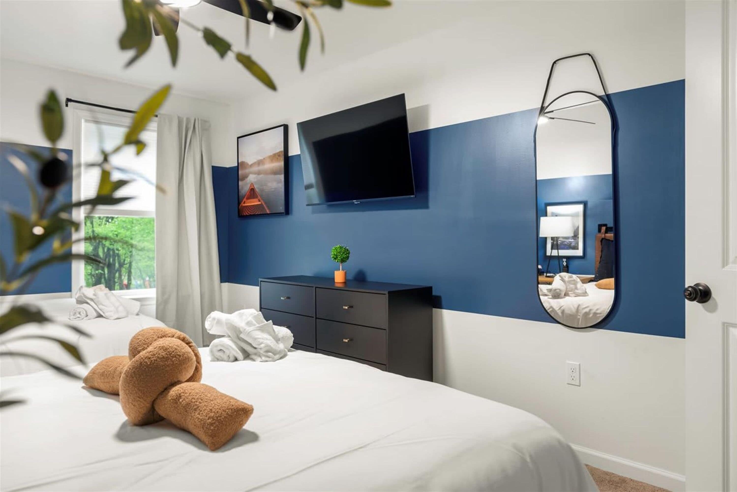 A hotel room with a bed, a dresser, a TV, and a mirror.