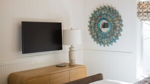 A bedroom with a bed, a television, a lamp, and a decorative mirror on the wall. - Luxury Lakefront 5 Br Home Hot Tub Arcade (Truckee)
