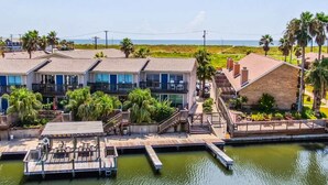 A waterfront property with a dock, multiple buildings, and a view of the ocean. - Scoop Deck Dock Pool Balcony Views (Corpus Christi)