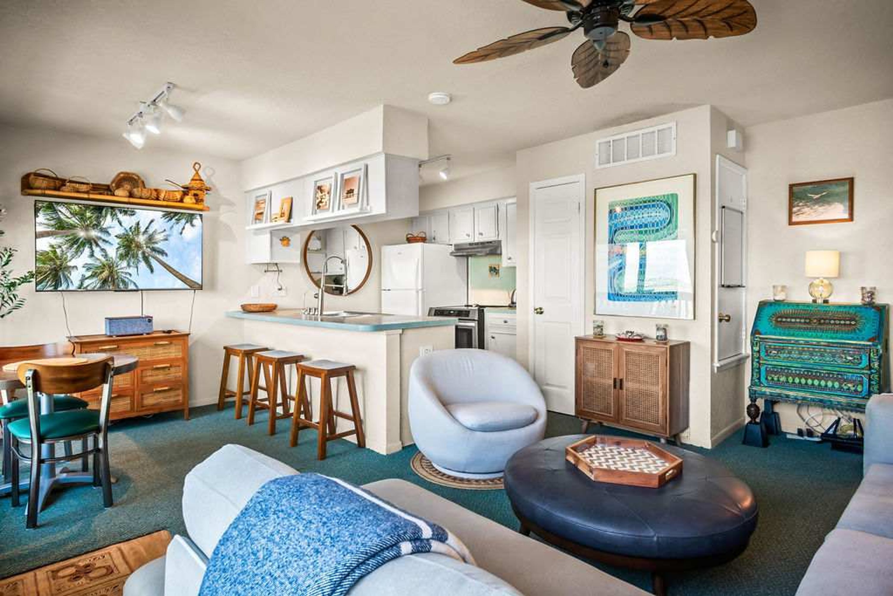 A compact living space with a kitchenette, a dining area, and a seating area with a sofa and ottoman.