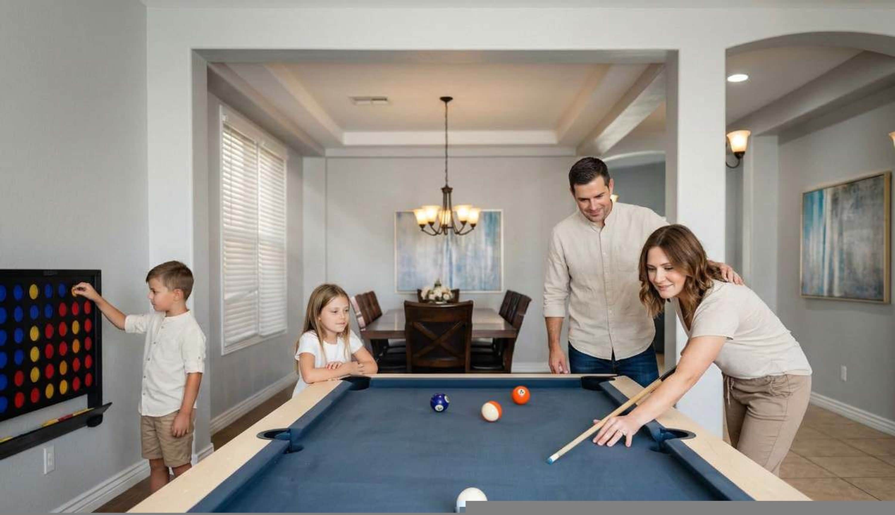 A family playing pool in a modern living room with a dining area in the background.