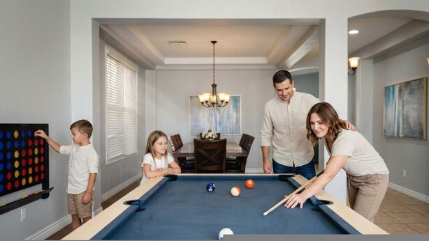 A family playing pool in a modern living room with a dining area in the background. - Desert Retreat Pool Fire Pit Family Games (Surprise)
