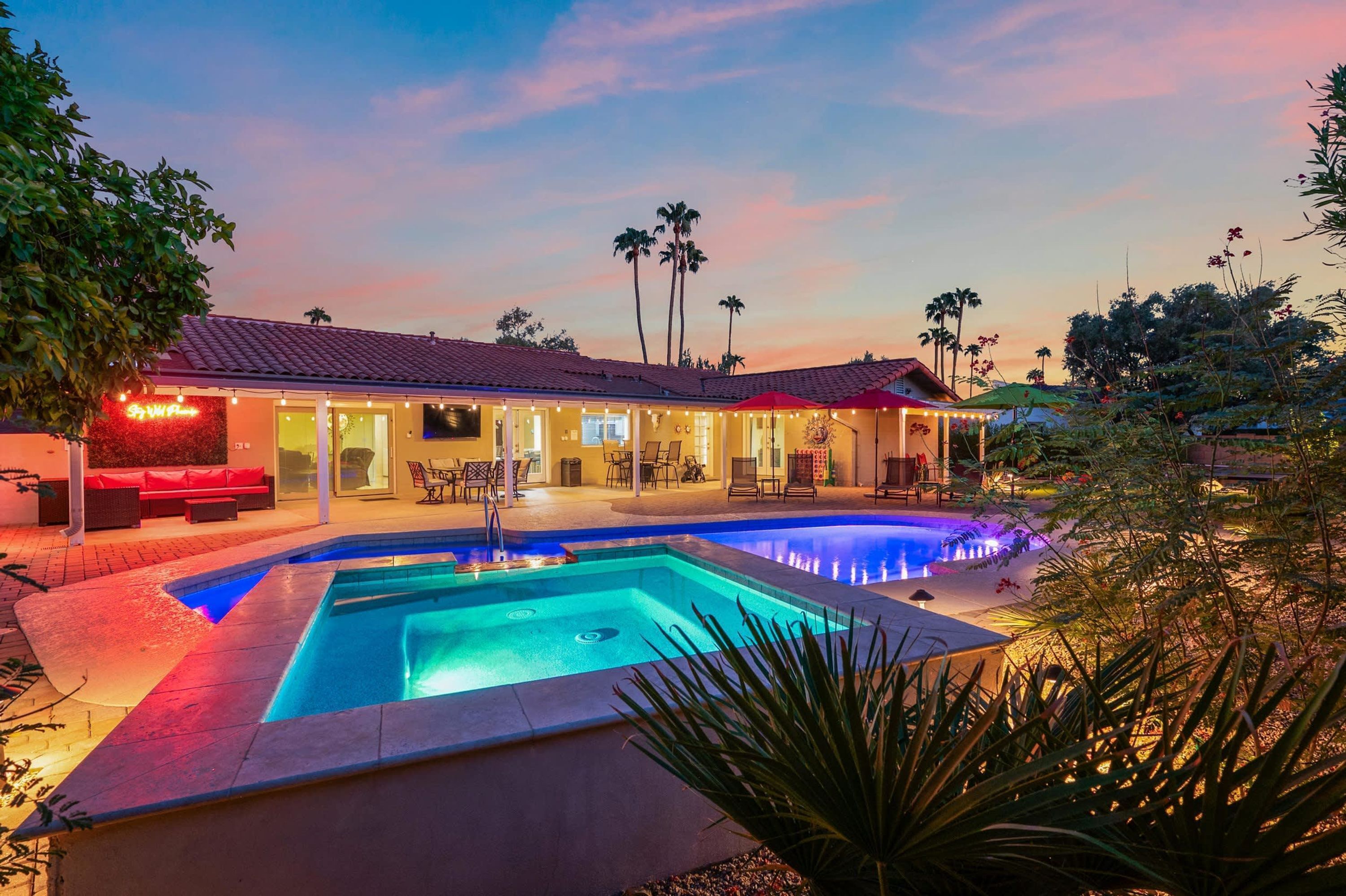 Un área de piscina con jacuzzi, mobiliario exterior y un porche cubierto.