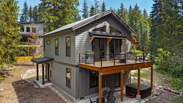 Eine zweistöckige Holzhütte mit Balkon, Sitzgelegenheiten im Freien und einer überdachten Terrasse.