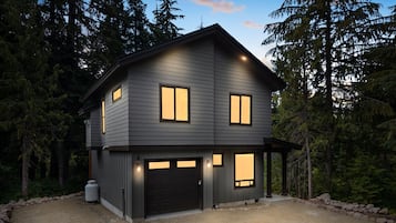 A two-story house with a garage, surrounded by trees.