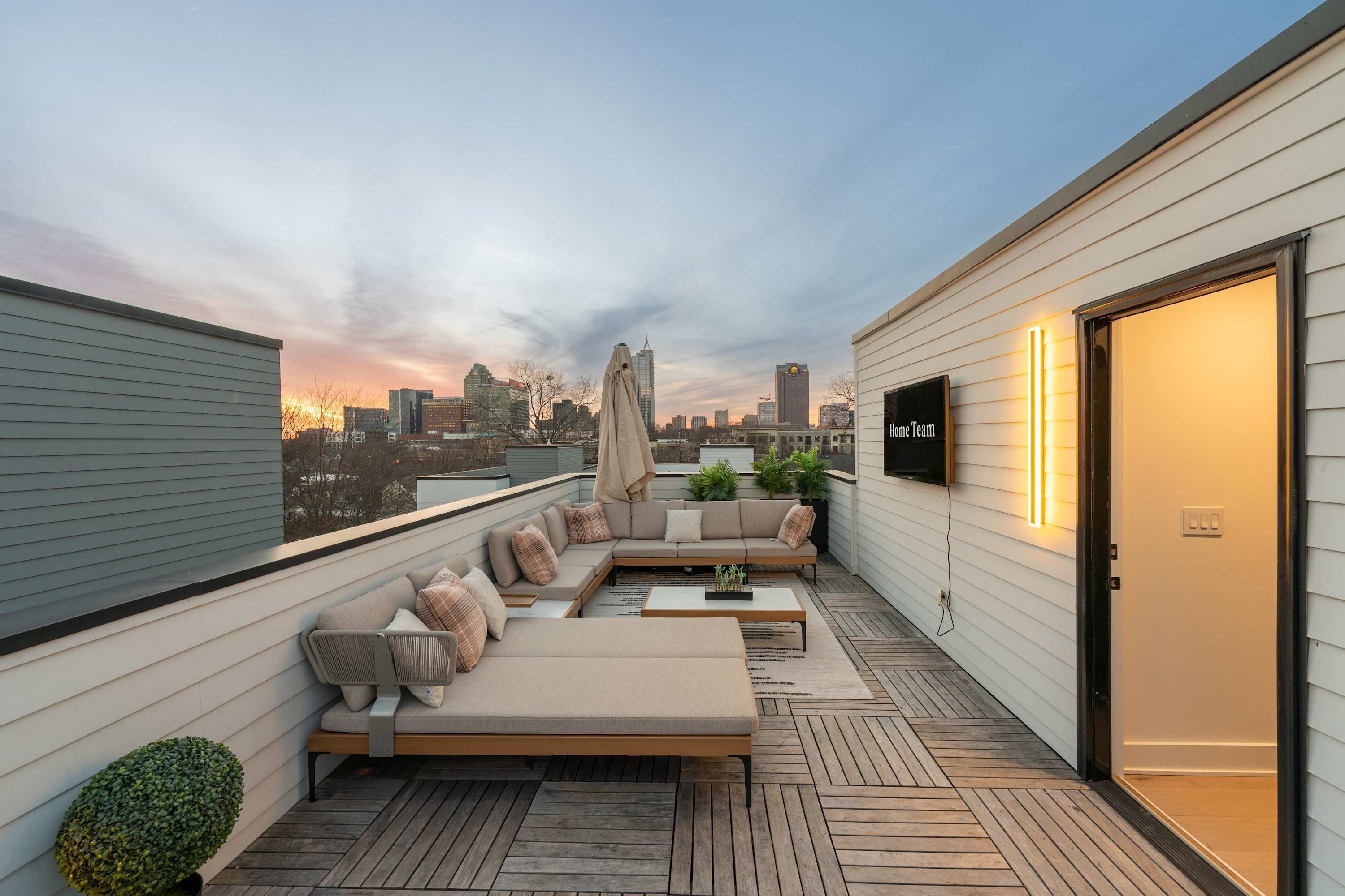 A rooftop terrace with a sofa set, a coffee table, and a TV mounted on the wall.