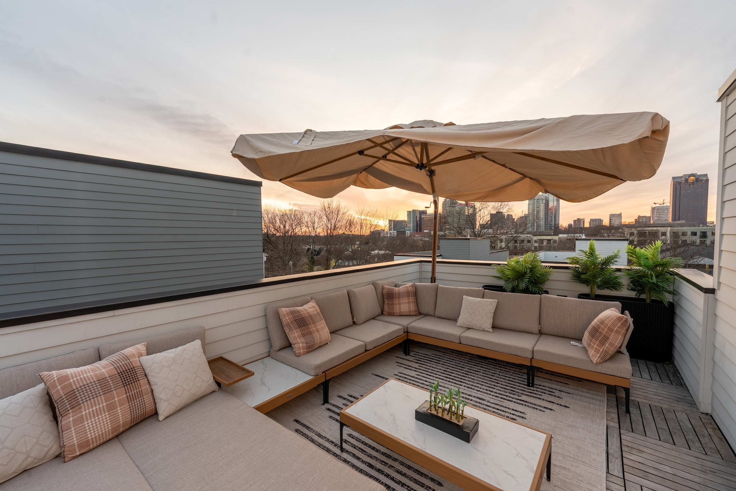 Een terras op het dak met een modulaire bank, een bijzettafeltje en een parasol.