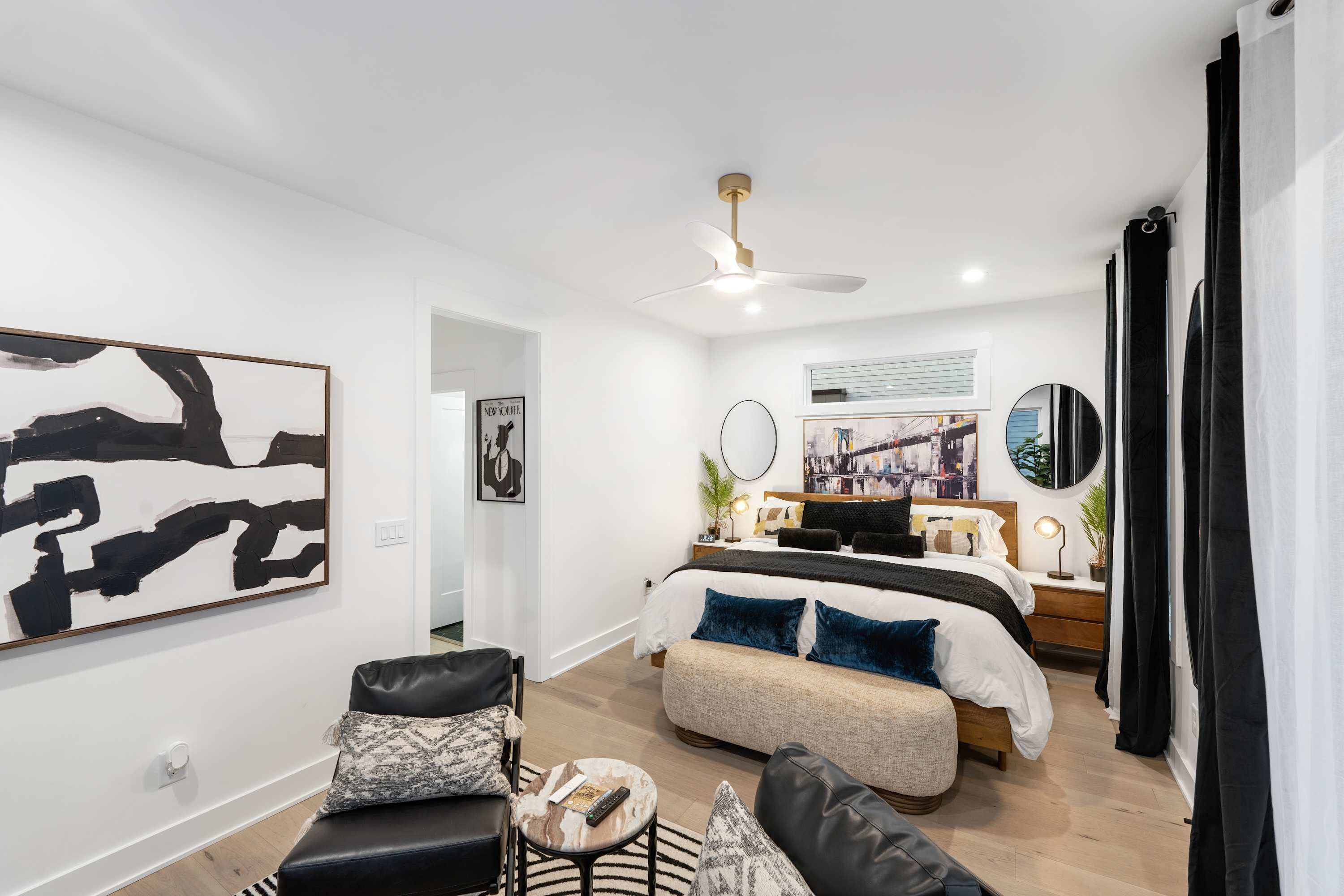 A modern bedroom with a bed, bedside tables, a ceiling fan, and artwork on the walls.