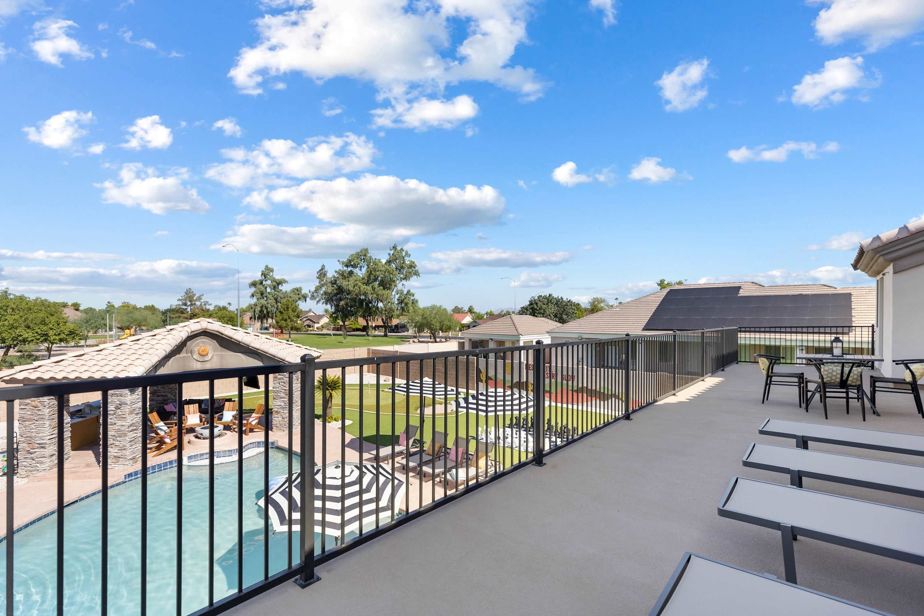 A rooftop pool area with a view of the surrounding landscape, including trees and a distant building.