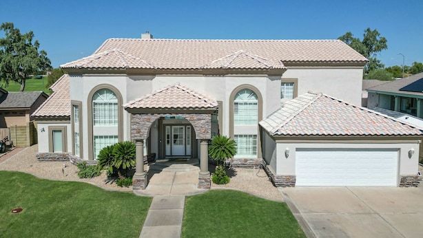 A two-story house with a tiled roof, a front entrance with a door, and a garage. - Luxury 6BR Retreat - Pool BBQ Theater and Games (Mesa)