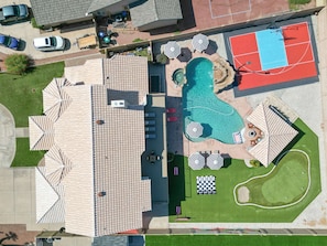 Eine Luftaufnahme einer Wohngegend mit Schwimmbad, Tennisplatz und Sitzgelegenheiten im Freien.