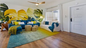 A living room with a blue sofa, a white sofa, and a coffee table. There is a large plant on the left side. - Poolside Retreat Sleeps 8 Putt Putt Hot Tub (Bradenton)