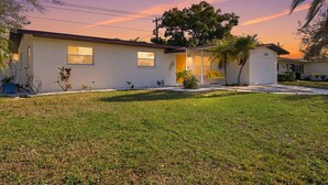 A single-story house with a front porch, a small garden, and a clear view of the sky. - Poolside Retreat Sleeps 8 Putt Putt Hot Tub (Bradenton)