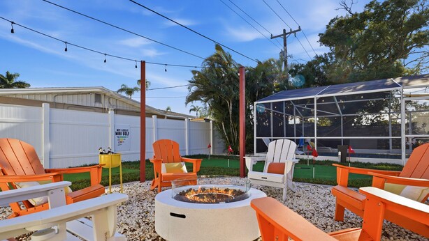 An outdoor seating area with orange chairs, a fire pit, and a covered structure. - Poolside Retreat Sleeps 8 Putt Putt Hot Tub (Bradenton)