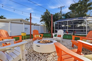An outdoor seating area with orange chairs, a fire pit, and a covered structure. - Poolside Retreat Sleeps 8 Putt Putt Hot Tub (Bradenton)
