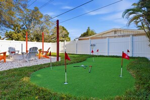 A mini golf course with artificial green turf, red flags, and a white fence. - Poolside Retreat Sleeps 8 Putt Putt Hot Tub (Bradenton)
